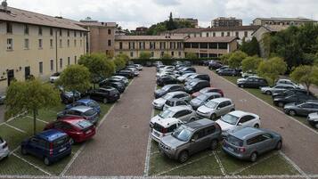 A parking lot with multiple rows of cars, surrounded by buildings with a uniform architectural style.
