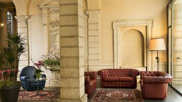 A lobby with a stone column, a blue armchair, a red sofa, and a lamp.
