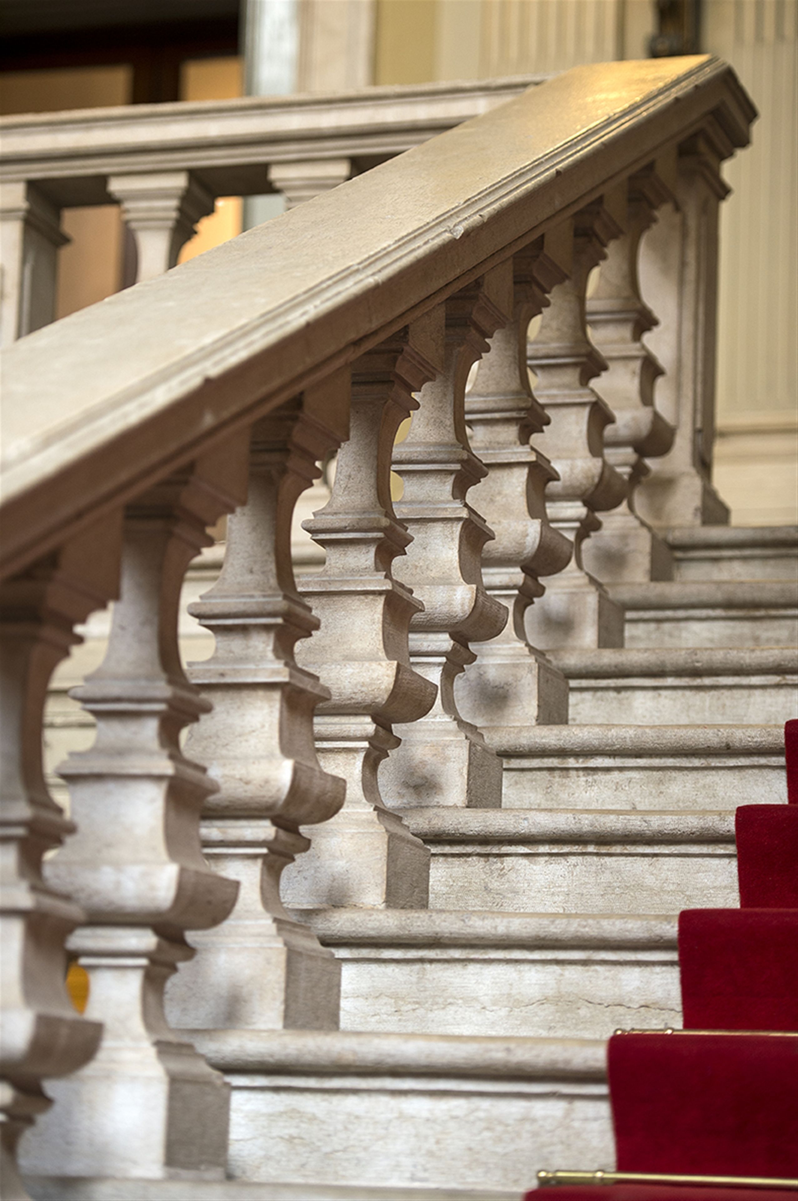 A grand staircase with ornate balustrades and red carpeted steps.