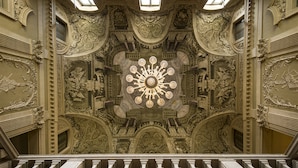 An ornate interior with a central chandelier, detailed wall carvings, and a symmetrical architectural design. - Centro Paolo VI (Brescia)