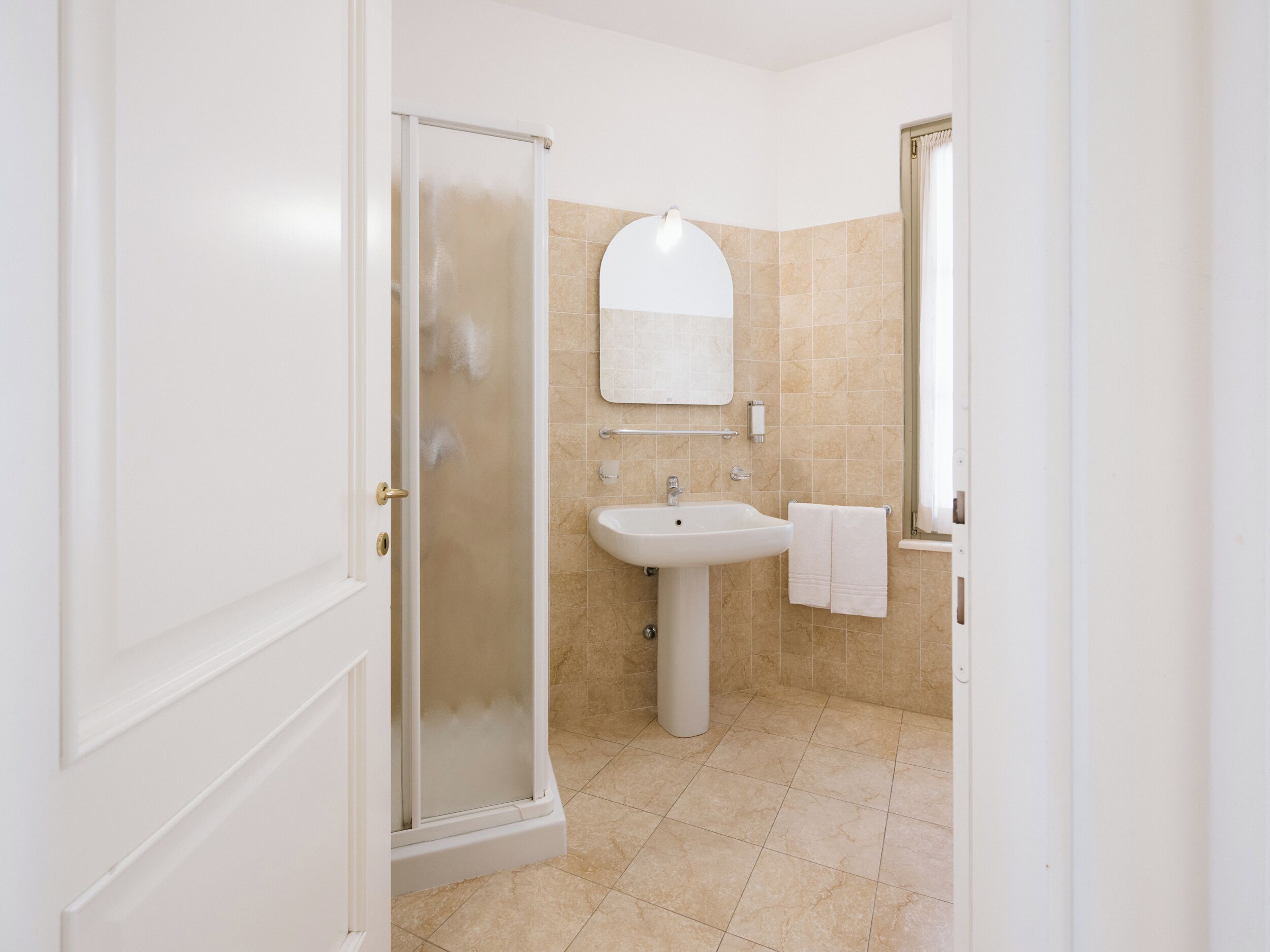 A bathroom with a shower, sink, and mirror.