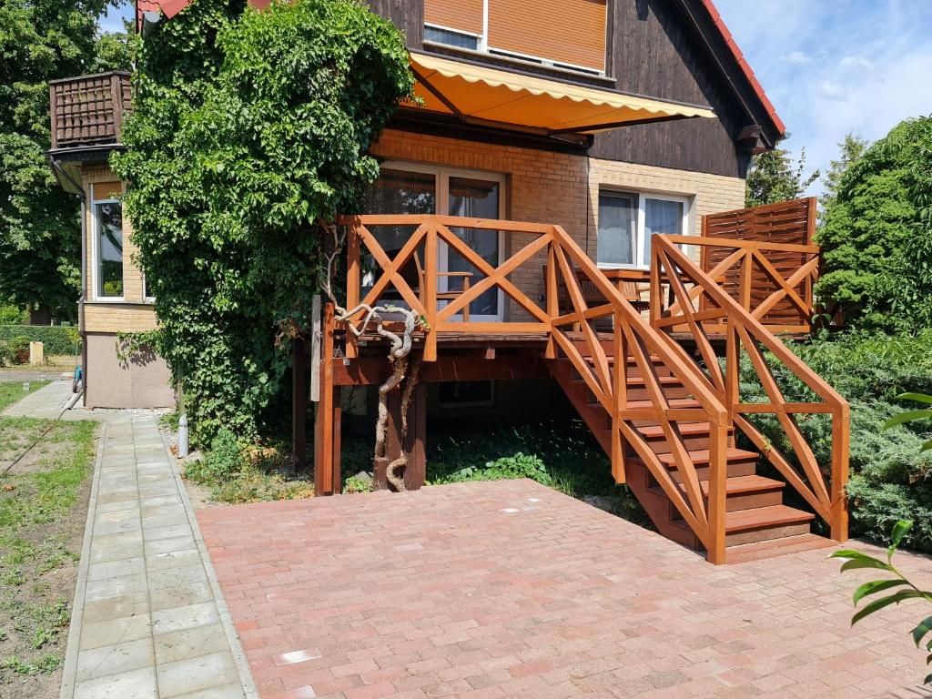 A wooden staircase leading to a deck with a brick pathway in front.