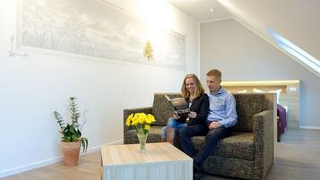 Un intérieur moderne avec un canapé, une petite table sur laquelle est posé un vase de fleurs et un tableau accroché au mur.