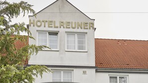 A hotel named "HOTELREUNER" with a glass entrance, surrounded by greenery. - Flair Hotel Reuner (Zossen)