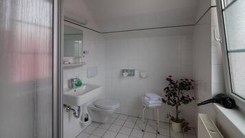 Een badkamer met een wit wastafel, toilet en een klein krukje met handdoeken.