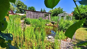 A garden with a pond, a gazebo, and a rustic building. - Flair Hotel Reuner (Zossen)