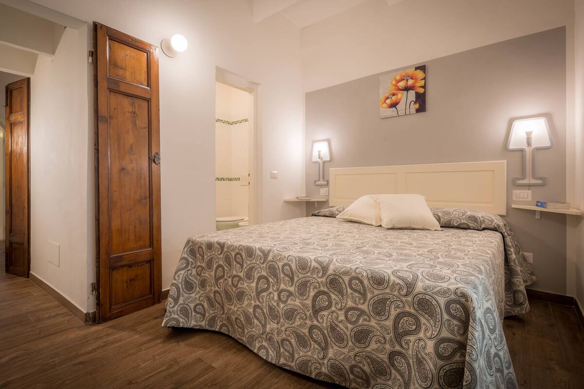 A bedroom with a bed, wooden door, and two bedside lamps.