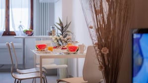 A breakfast table with a bowl of fruit, a slice of watermelon, and a mug. - Novella Apartments (Florence)