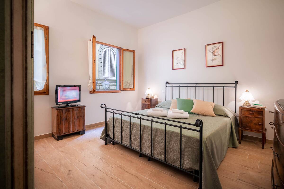 A bedroom with a bed, a television, a nightstand, and a dresser.