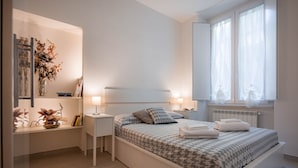 A modern bedroom with a large bed, bedside tables, a mirror, and a ceiling fan. - Novella Apartments (Florence)