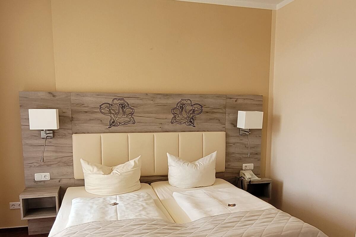 A hotel room with a large bed, two bedside tables, and a headboard with floral designs.