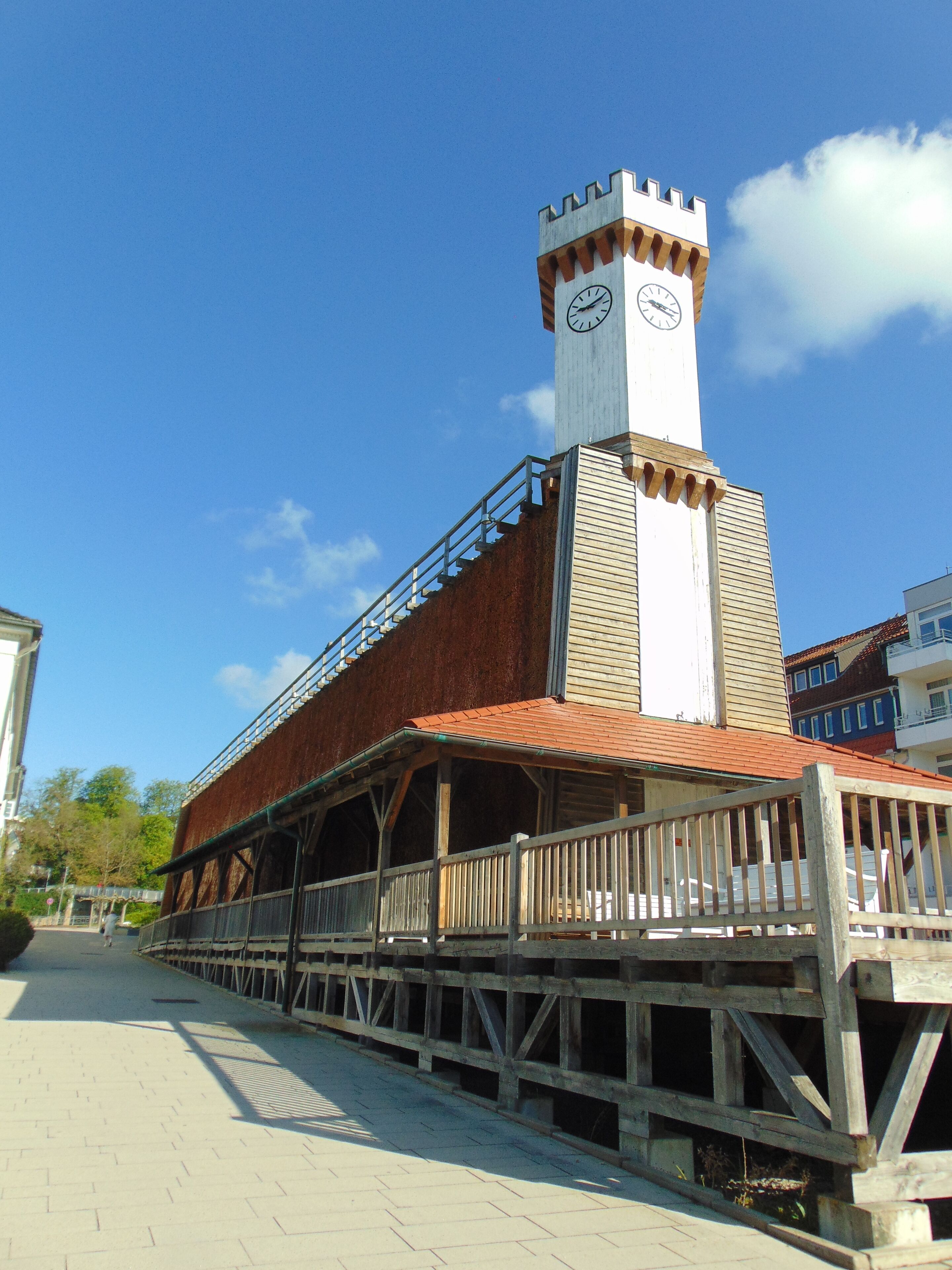 A building with a clock tower, wooden deck, and a brick facade.