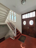 A staircase with white balusters, a red carpeted landing, and a wooden door with two windows.
