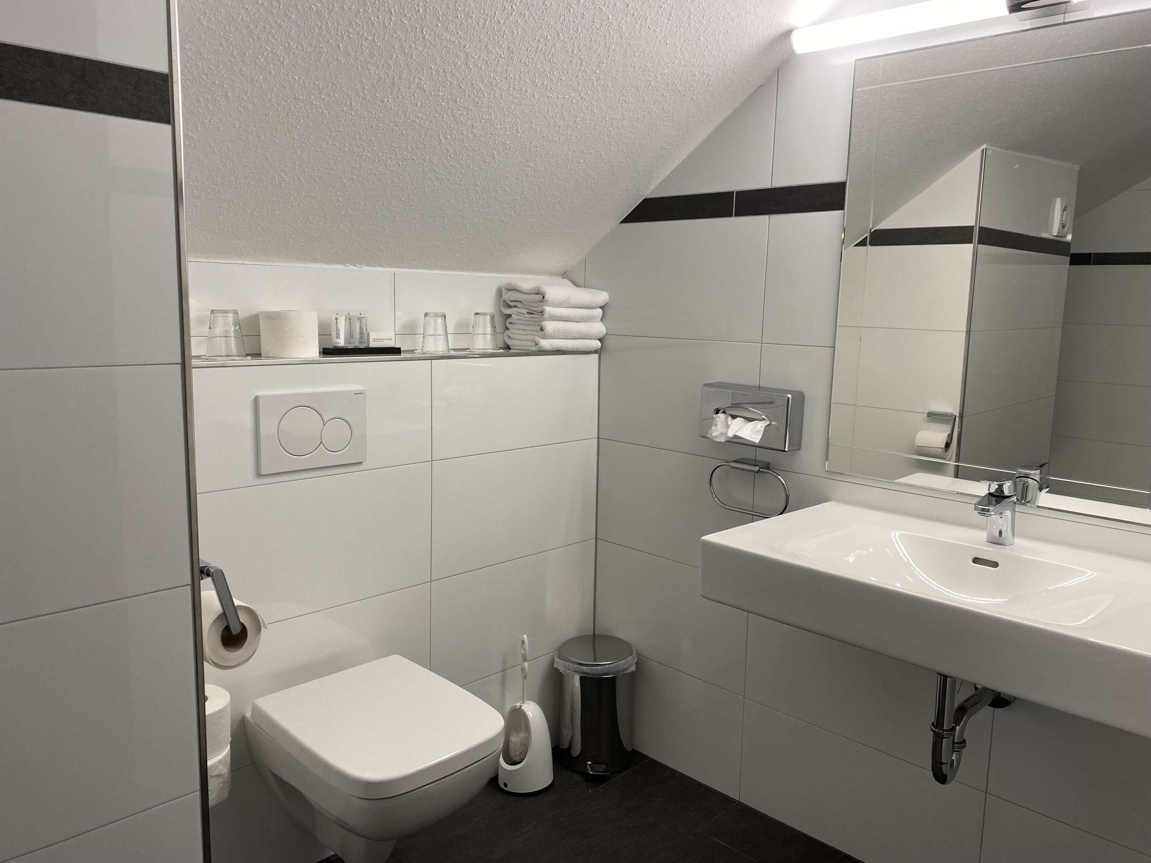 Une salle de bain moderne équipée de toilettes, d’un bidet, d’un lavabo et d’un distributeur de serviettes.