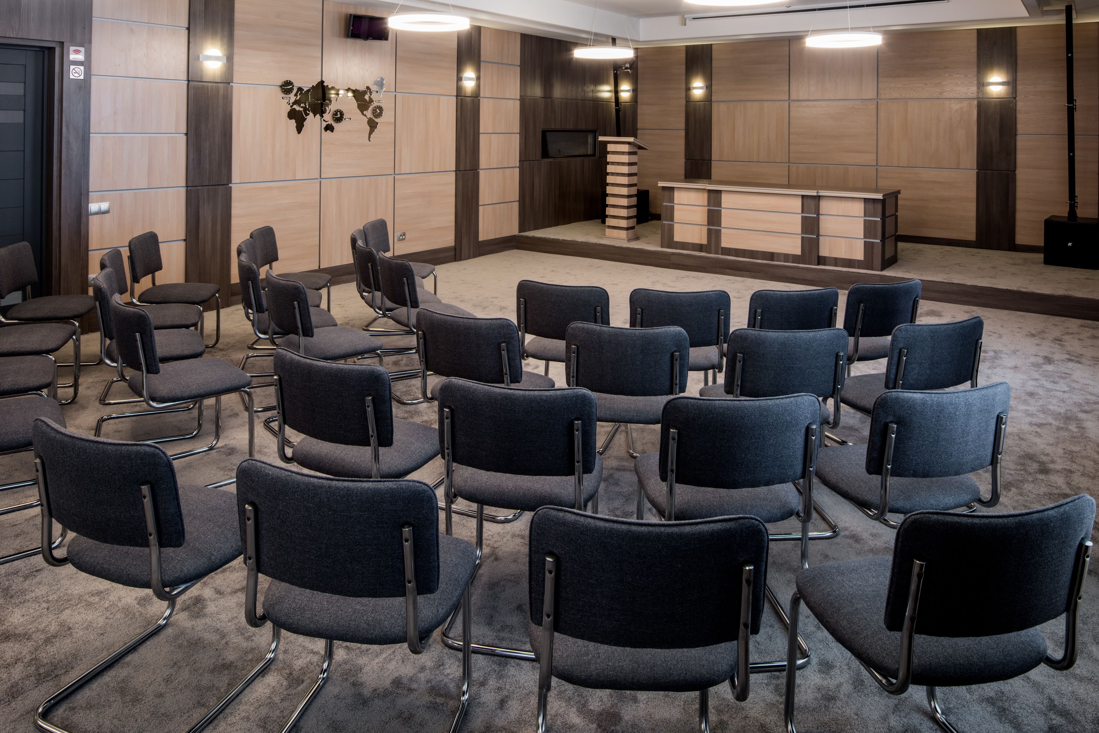 A conference room with rows of chairs, a reception desk, and a television.