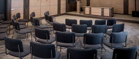 A conference room with rows of chairs, a reception desk, and a television.