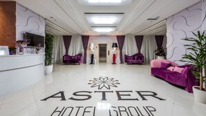 A hotel lobby with a reception desk, purple sofas, and a sign reading "ASTER HOTEL GROUP". - Aster Hotel Group (Tashkent)