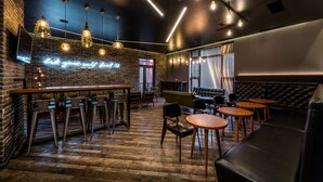 A bar area with a wooden counter, metal stools, and hanging pendant lights. - Aster Hotel Group (Tashkent)