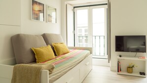 A bedroom with a bed, a TV, a window, and a door. - Severa Apartments (Lisbon)