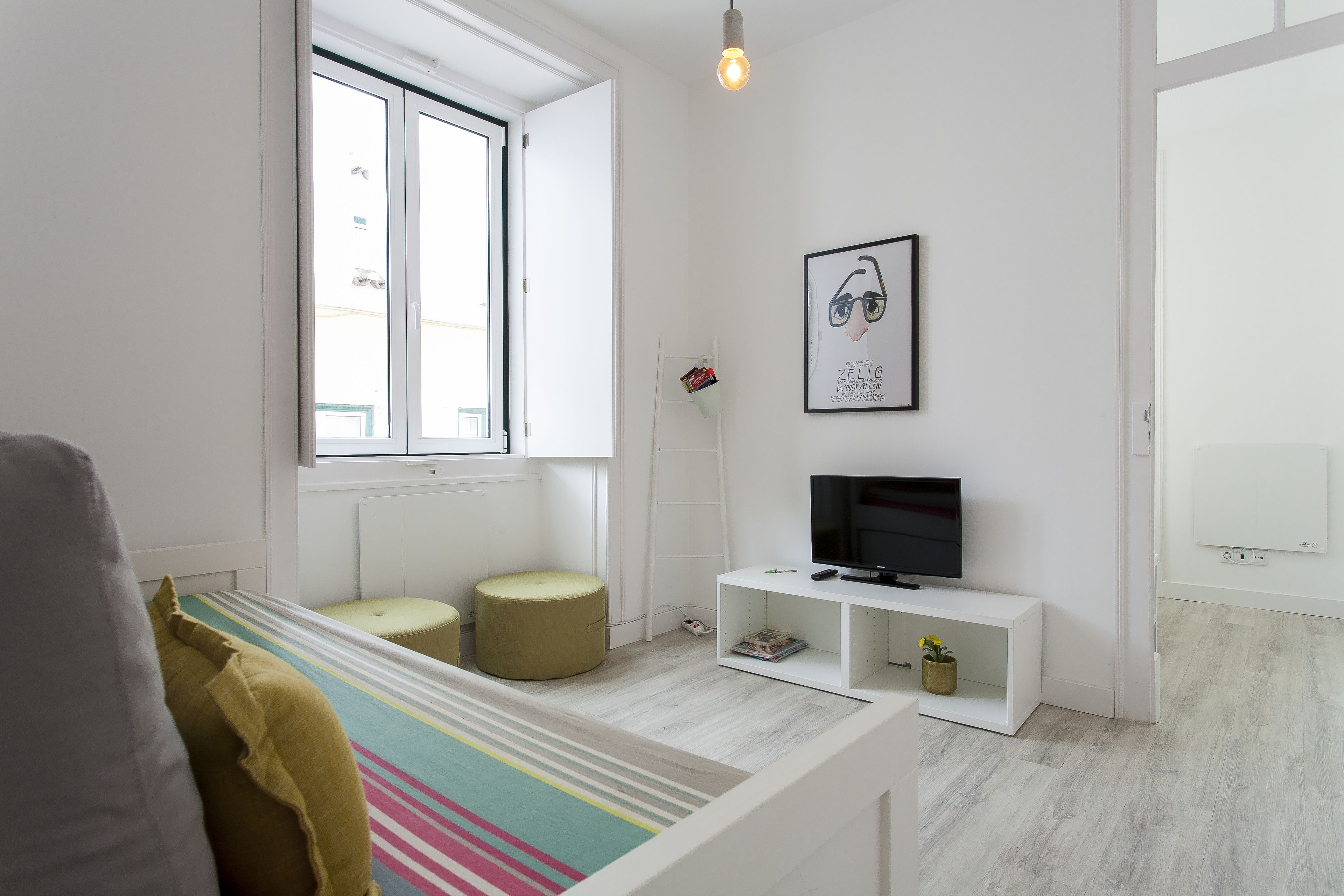 Een moderne, minimalistisch ingerichte slaapkamer met een bed, een televisie en een raam.