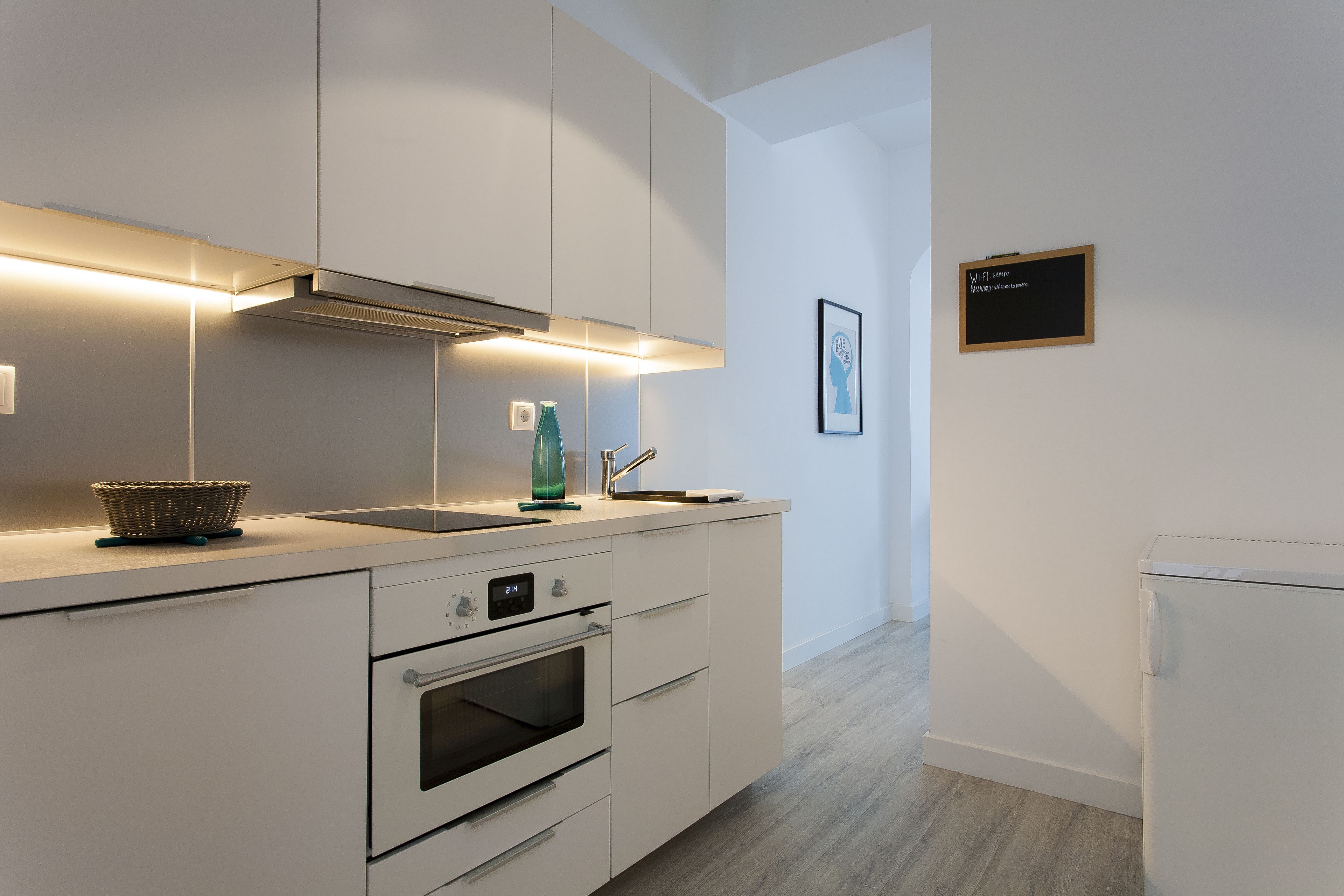 A modern kitchen with built-in appliances, a sink, and a small refrigerator.