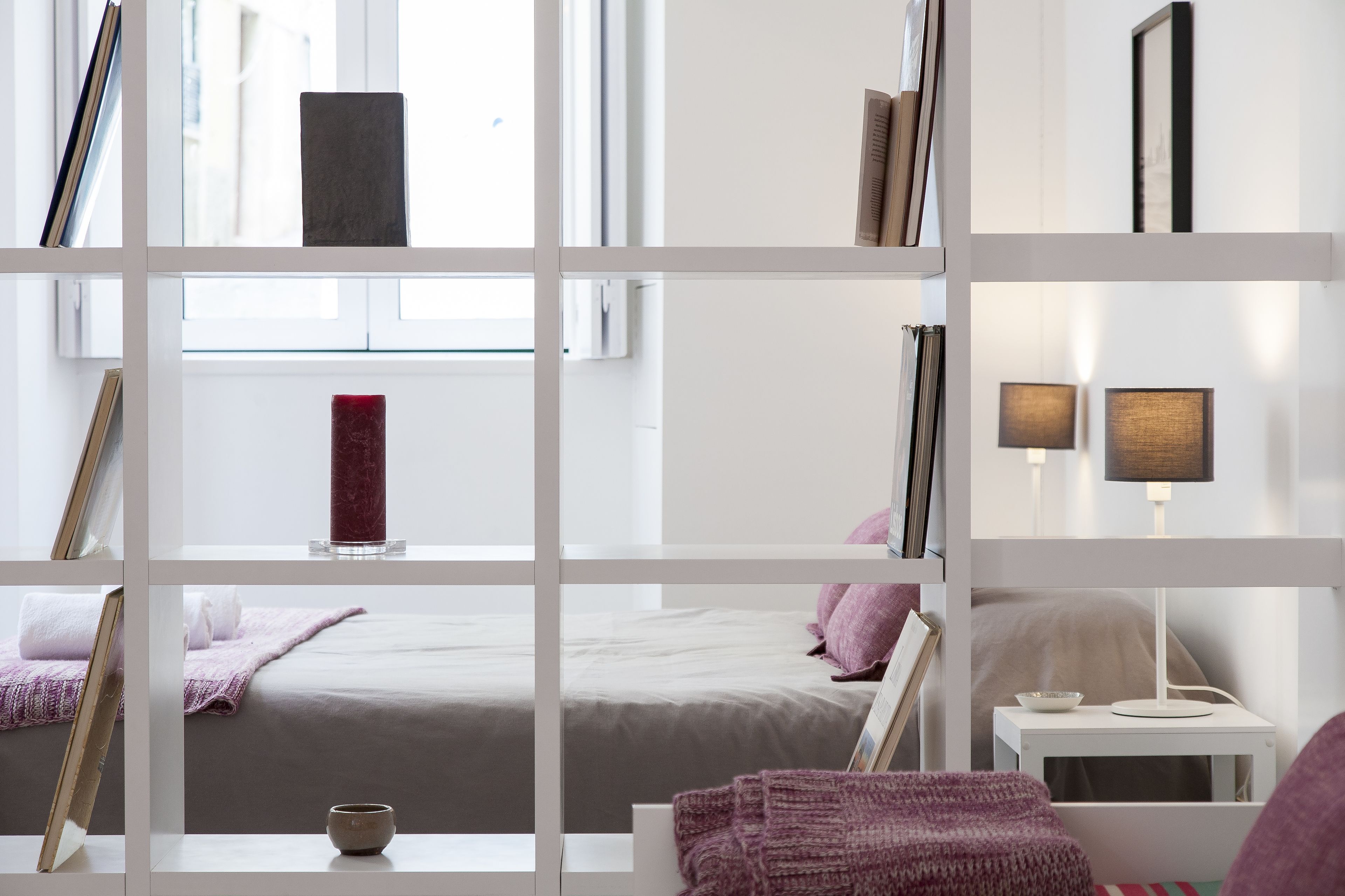A modern bedroom with a bed, bedside table, and a window.