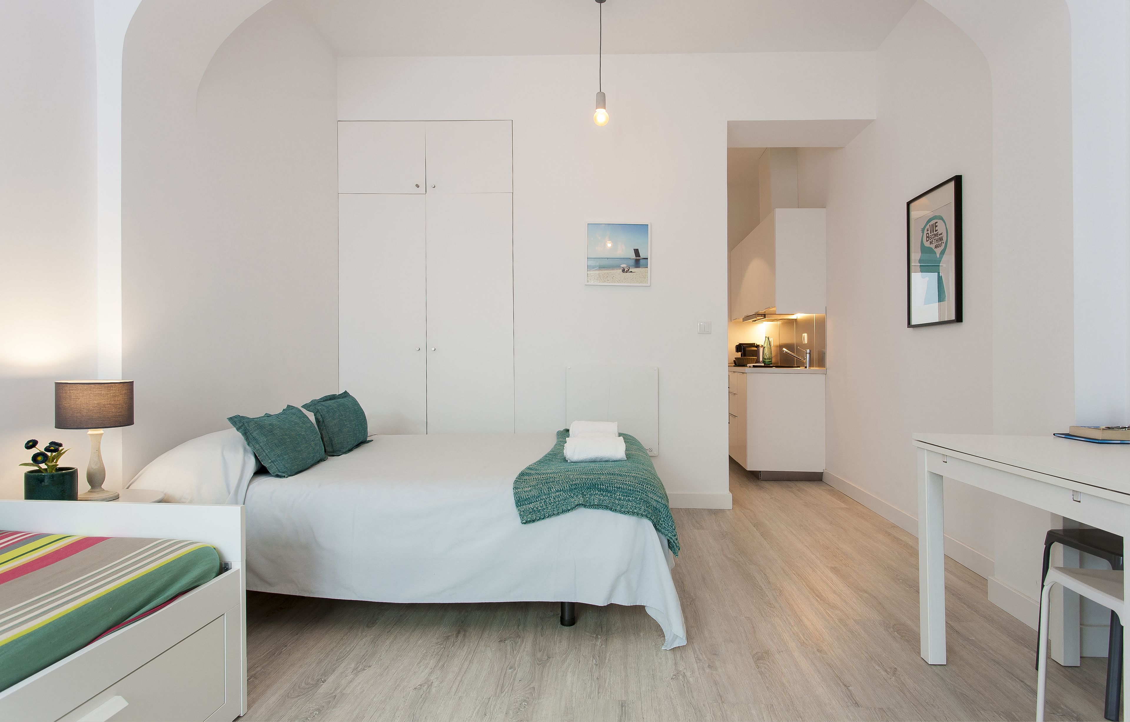 A modern bedroom with a bed, bedside table, and a desk.