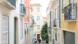 A narrow cobblestone street flanked by buildings with balconies and shutters. - Severa Apartments (Lisbon)
