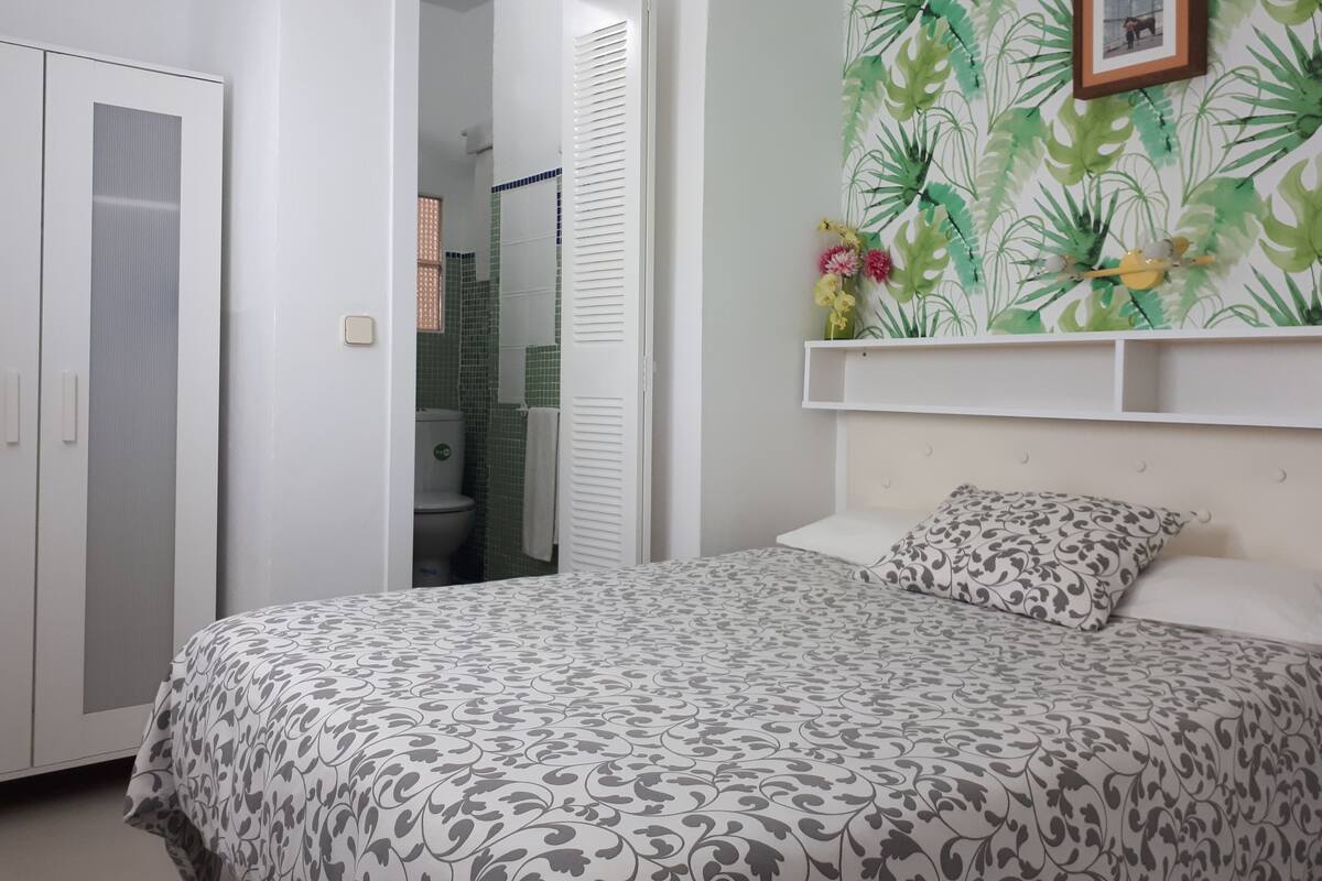 A bedroom with a bed, a wardrobe, and a bathroom visible through an open door.