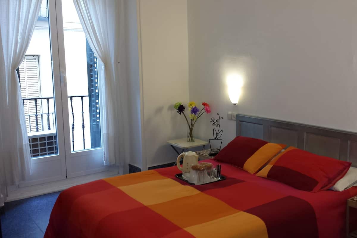 A hotel room with a large bed, a bedside table with a lamp, and a window with curtains.