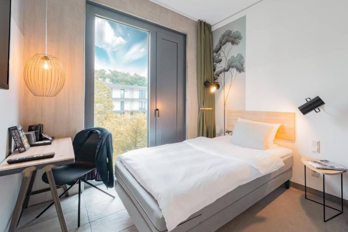 Een moderne hotelkamer met een bed, bureau, stoel en uitzicht op het groen.