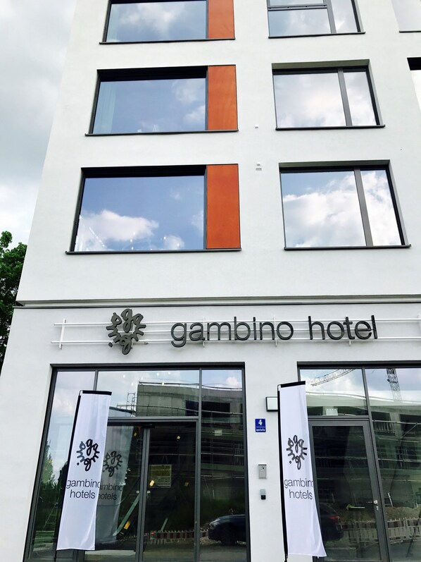 Un edificio con un letrero que dice "gambino hotel" y dos banderines colgados en la entrada.