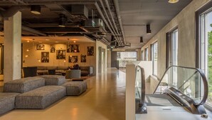 Un vestíbulo amplio con un diseño moderno, que cuenta con una zona de estar con sofás y una escalera con cinta transportadora.