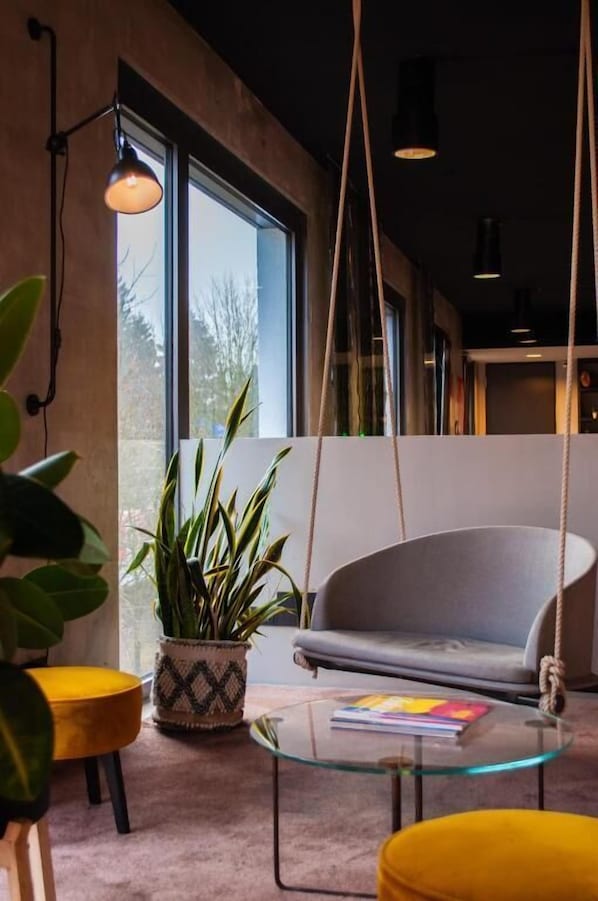 Un interior moderno con un sofá, lámpara colgante y una mesa de vidrio.