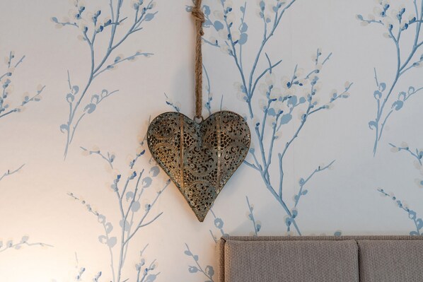 A wall with a floral pattern and a hanging heart-shaped ornament. - Afon Rhaiadr Country House (Dolgellau)