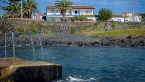 Un hotel frente al mar con muro de piedra, piscina y vistas al océano.