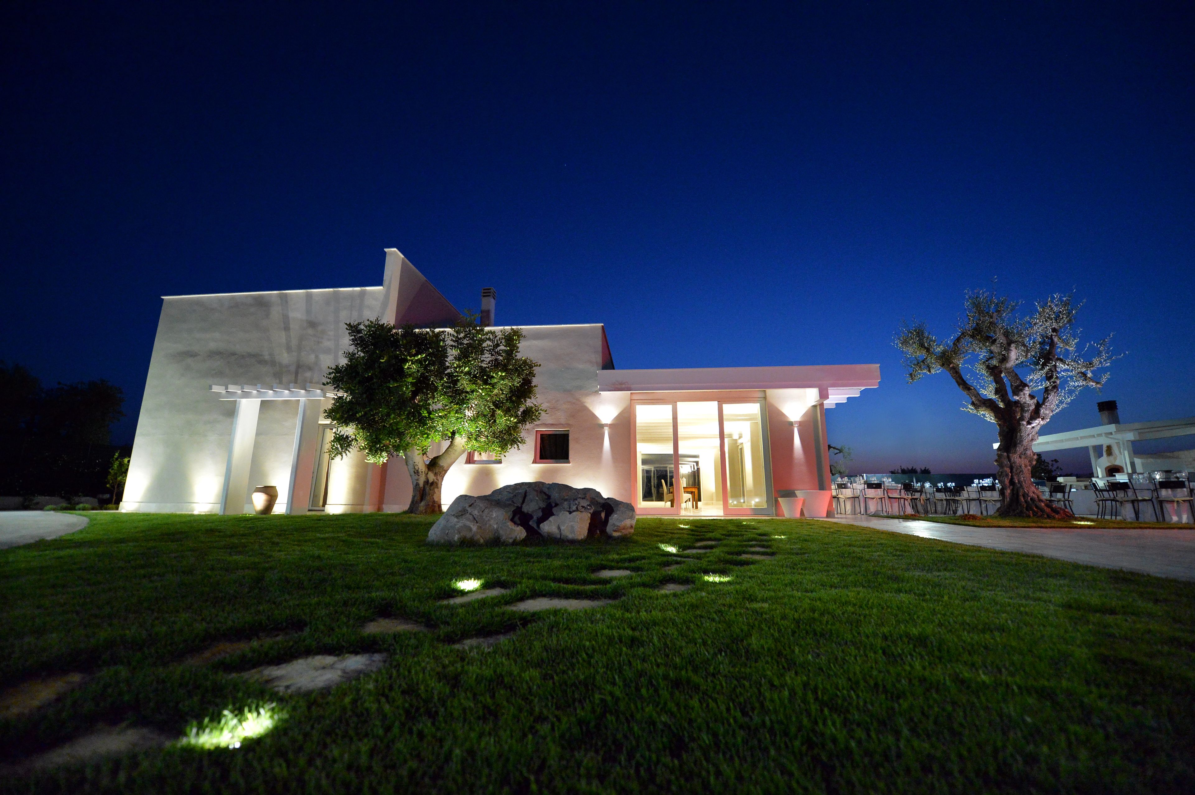 A modern building with a well-maintained lawn, large rocks, and a tree.