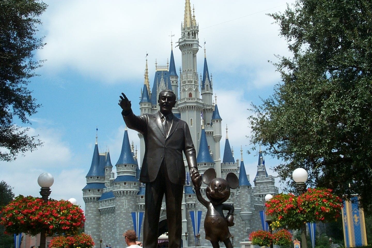 A statue of a man in a suit with a child in front of a castle-like building.