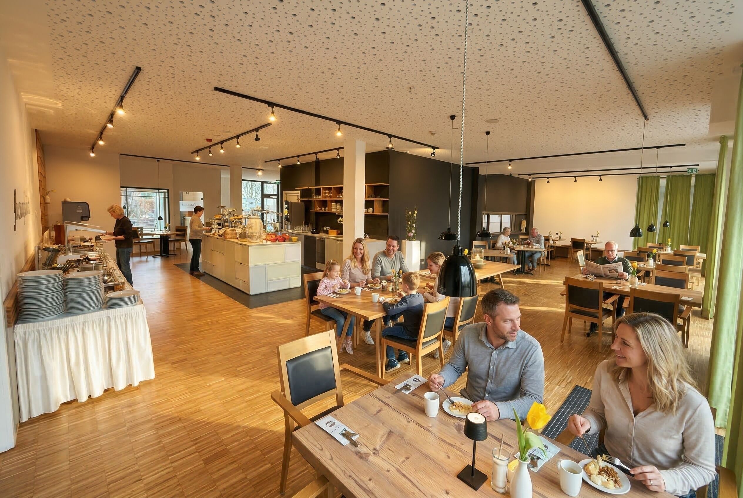 A spacious dining area with wooden tables and chairs, a buffet setup, and a kitchen in the background.