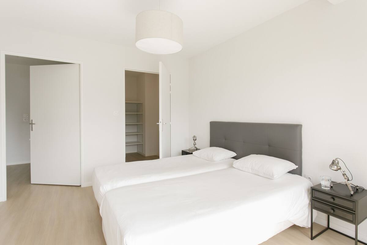 Un dormitorio con cama, mesita de noche, lámpara y armario.