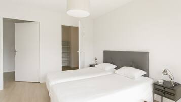 Un dormitorio con cama, mesita de noche, lámpara y armario.