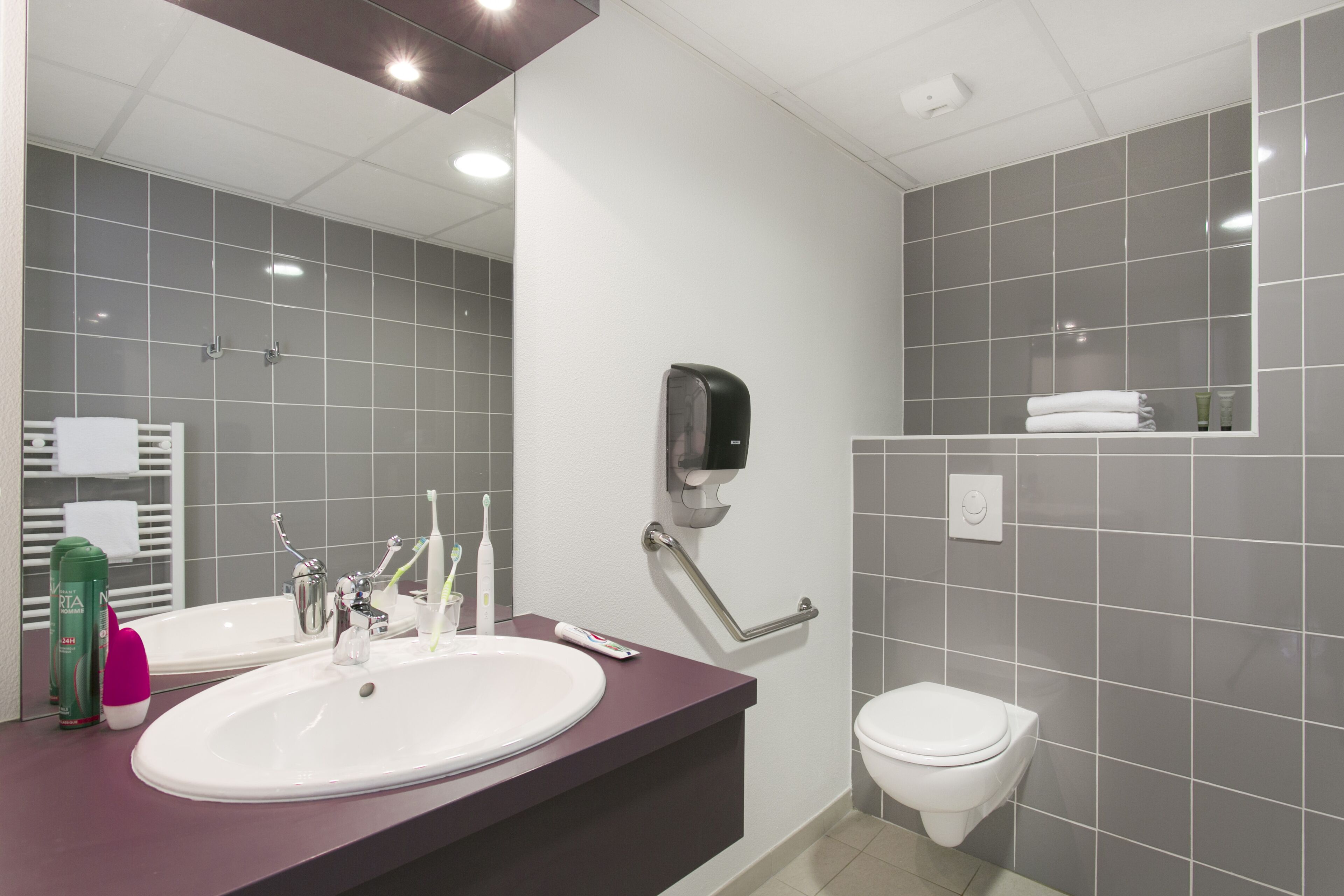A modern bathroom with two sinks, a toilet, and a hand dryer.