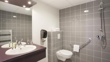 A modern bathroom with two sinks, a toilet, a shower, and a towel rack.