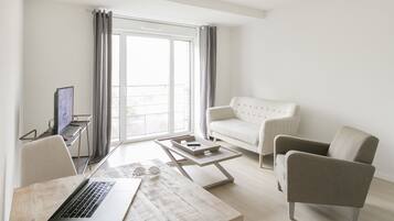 Un salon moderne avec un ordinateur portable posé sur une table en bois, un canapé et une table basse.