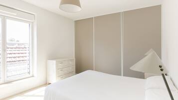 A bedroom with a bed, a dresser, a wardrobe, and a window with blinds.