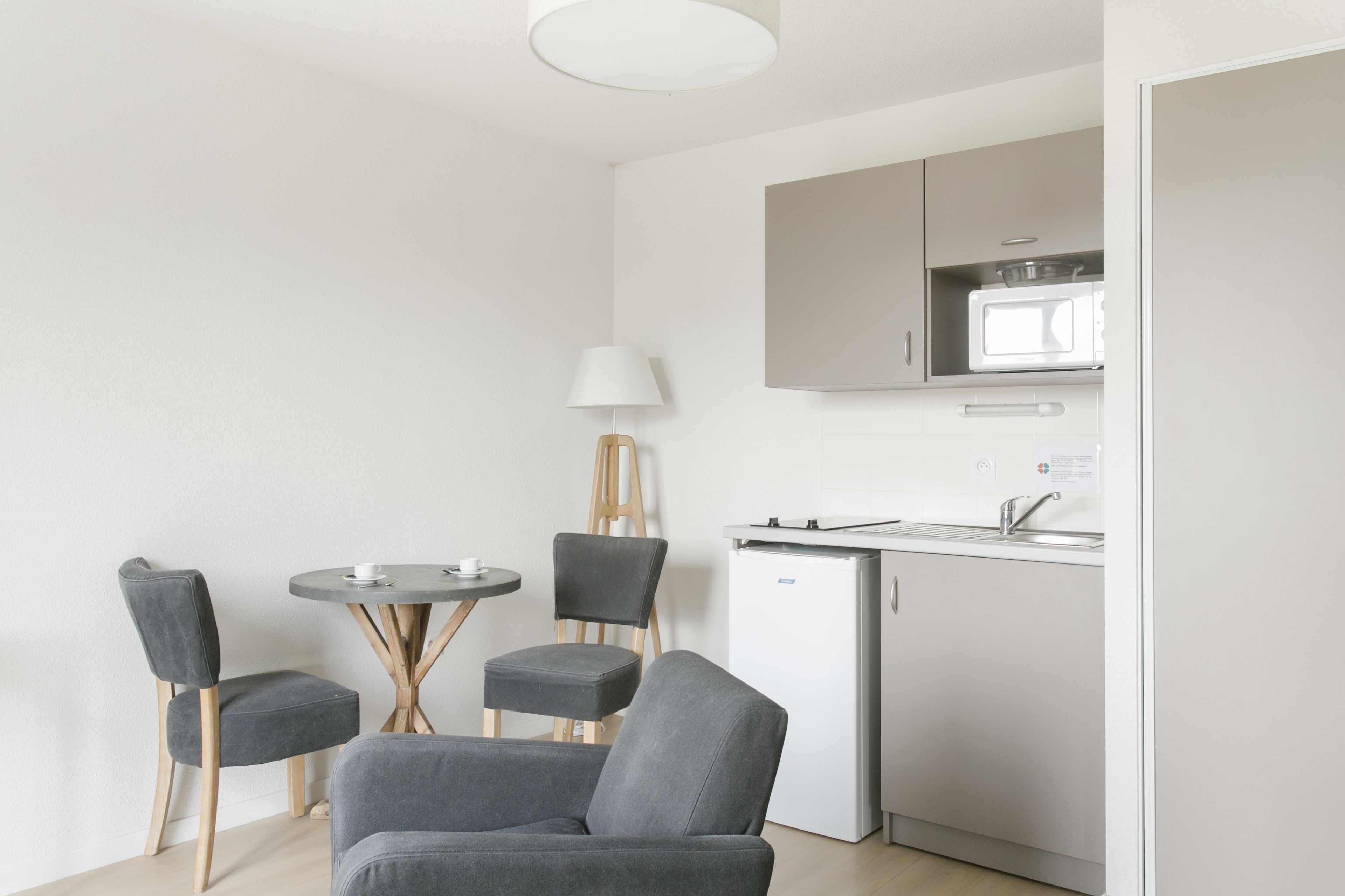 A modern kitchen with a microwave, sink, and cabinets. There is a dining area with a table and chairs.