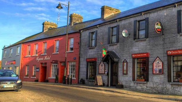A row of buildings with signs for local businesses, including a pub and a music venue. - Ryan's Hotel (Cong)