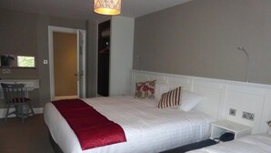 A hotel room with two beds, a desk, and a chair. - Ryan's Hotel (Cong)
