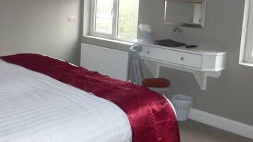 Un dormitorio con cama, cómoda, espejo y ventana.