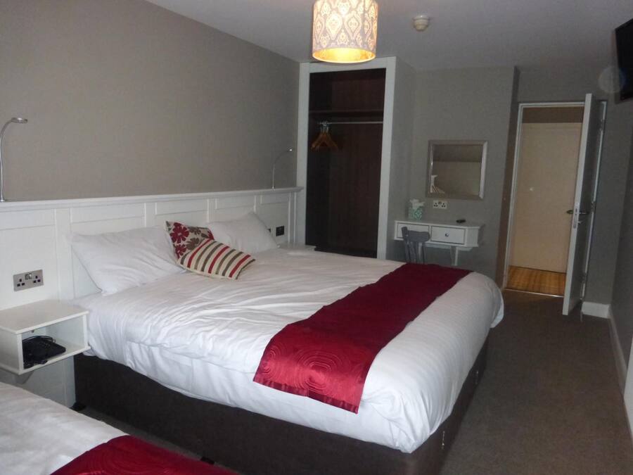 A hotel room with a bed, bedside table, and a desk with a chair.
